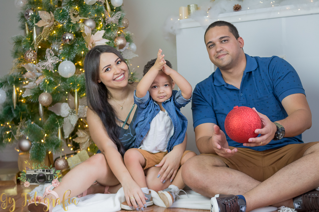 No pé da arvore de natal e a lareira a familia reunida pra sessão de natal. Ensaio fotográfico feito em estúdio, fotografo especializado em ensaios de bebes e crianças, Mini sessão de natal, momento registrado pela fotógrafa Giscellayne - Gy Fotografia.