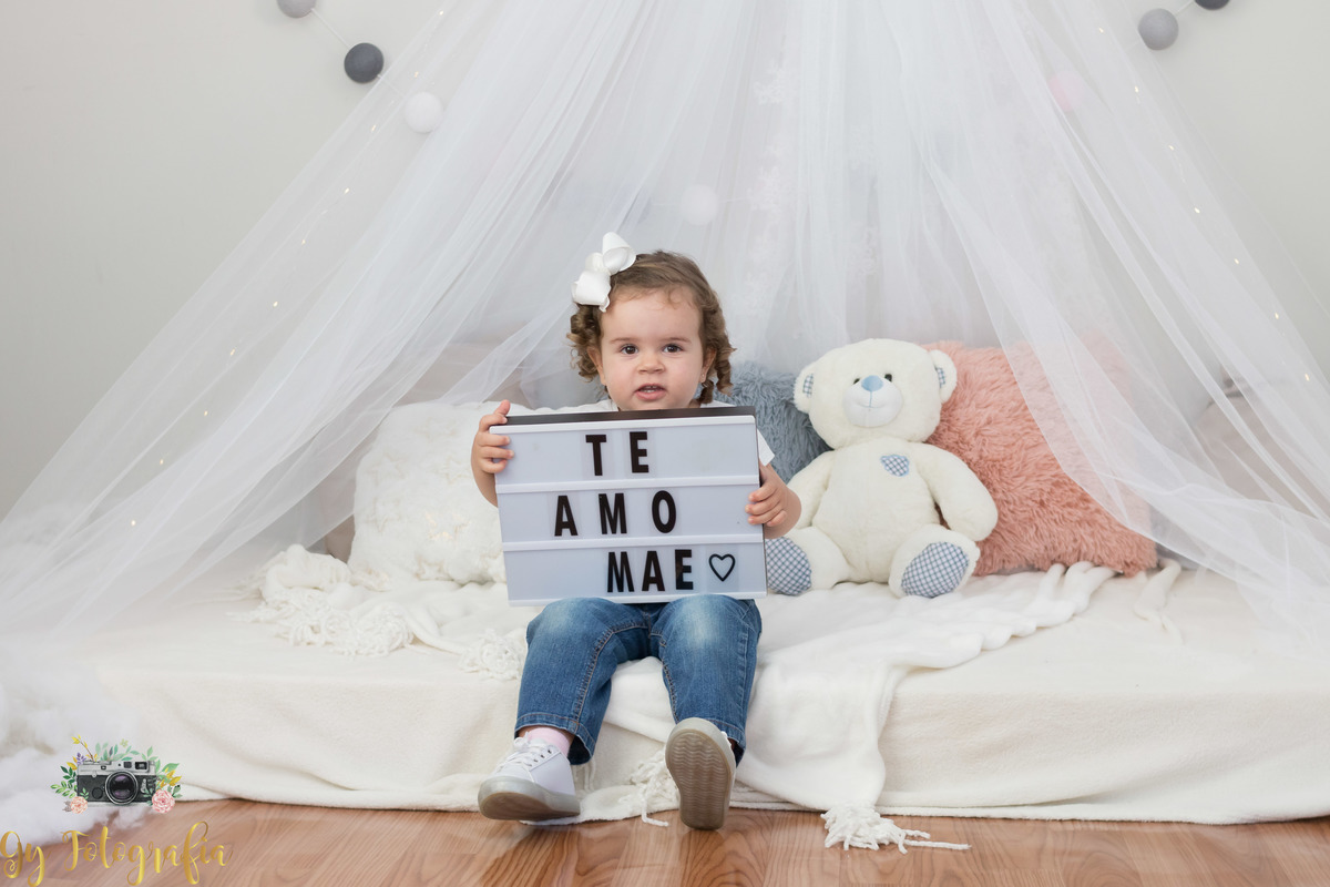 Helena segurando a plaquinha do eu te amo mãe! Ensaio de dia das mães em estúdio. Fotografo em Londrina especializado em ensaios de família. Momento registrado pela fotografa Giscellayne | Gy Fotografia