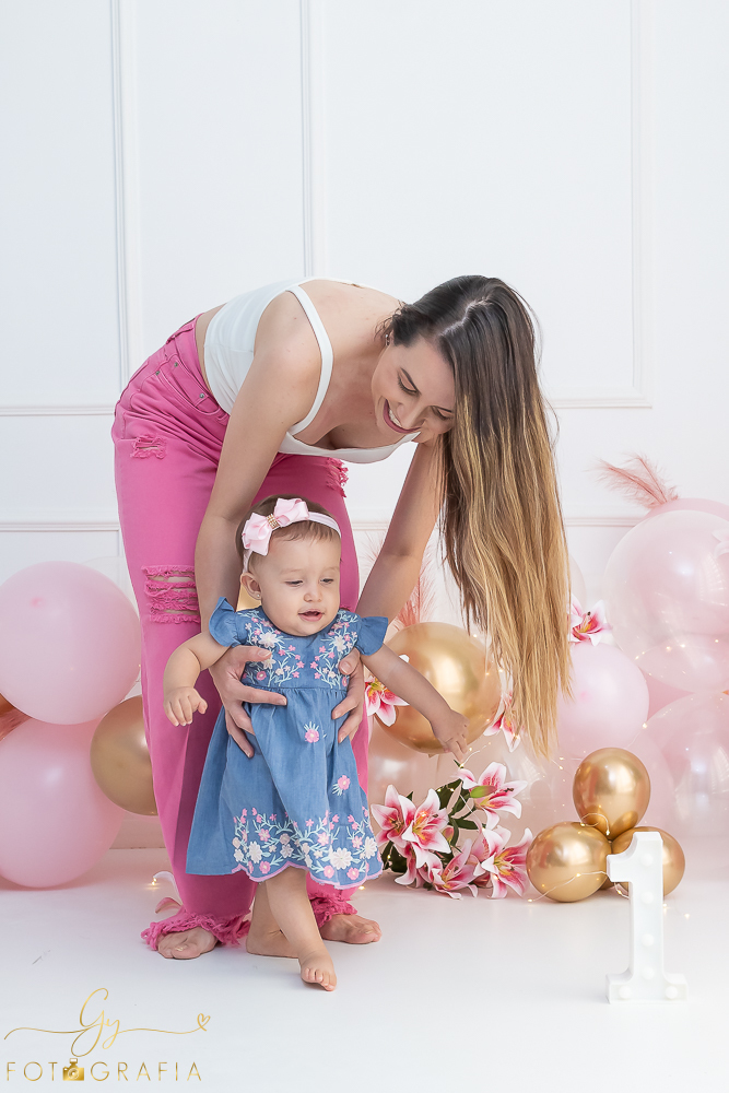 Ensaio smash the cake em estúdio. cenário com balões rosa e plumas. fotógrafo em Londrina especializado em ensaio de bebês e crianças. Ensaio de aniversário. Momento registrado pela fotografa Giscellayne - Gy Fotografia.