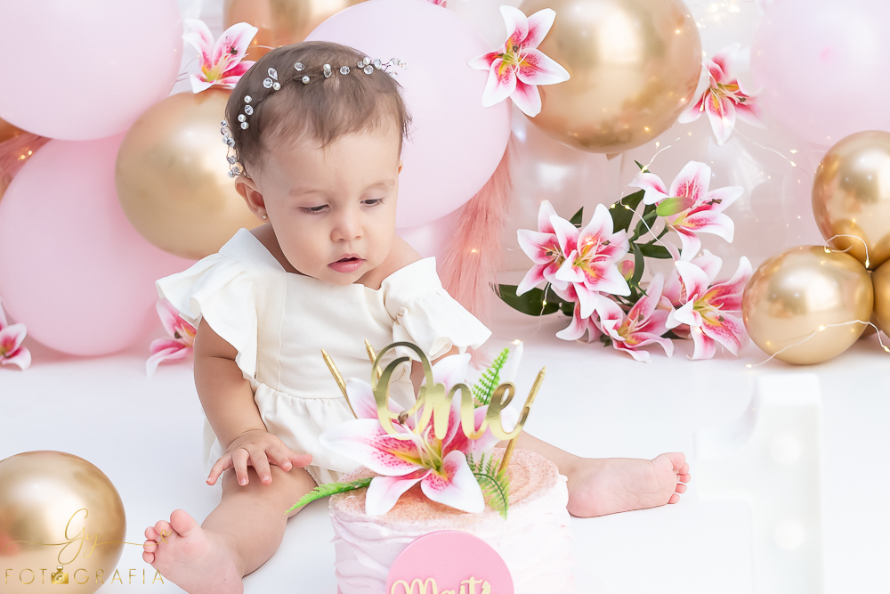 Ensaio smash the cake em estúdio. cenário com balões rosa e plumas. fotógrafo em Londrina especializado em ensaio de bebês e crianças. Ensaio de aniversário. Momento registrado pela fotografa Giscellayne - Gy Fotografia.
