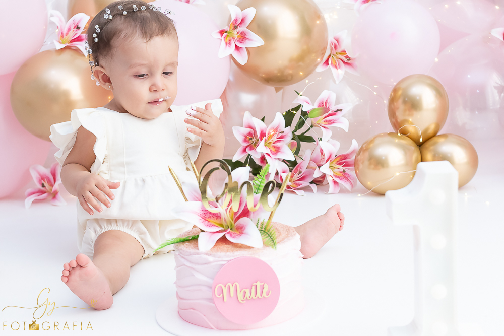 Ensaio smash the cake em estúdio. cenário com balões rosa e plumas. fotógrafo em Londrina especializado em ensaio de bebês e crianças. Ensaio de aniversário. Momento registrado pela fotografa Giscellayne - Gy Fotografia.