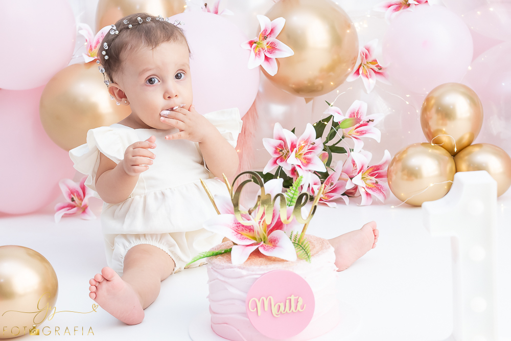 Ensaio smash the cake em estúdio. cenário com balões rosa e plumas. fotógrafo em Londrina especializado em ensaio de bebês e crianças. Ensaio de aniversário. Momento registrado pela fotografa Giscellayne - Gy Fotografia.