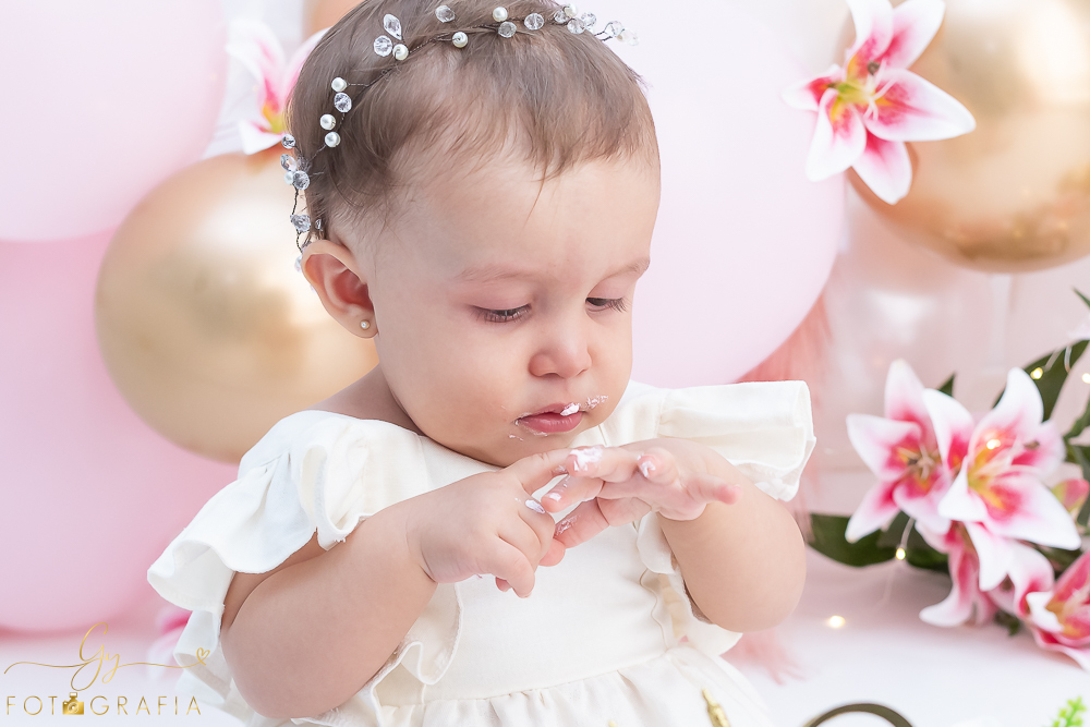 Ensaio smash the cake em estúdio. cenário com balões rosa e plumas. fotógrafo em Londrina especializado em ensaio de bebês e crianças. Ensaio de aniversário. Momento registrado pela fotografa Giscellayne - Gy Fotografia.