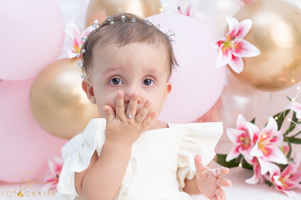 Ensaio smash the cake em estúdio. cenário com balões rosa e plumas. fotógrafo em Londrina especializado em ensaio de bebês e crianças. Ensaio de aniversário. Momento registrado pela fotografa Giscellayne - Gy Fotografia.