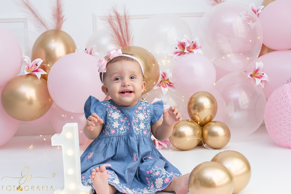 Ensaio smash the cake em estúdio. cenário com balões rosa e plumas. fotógrafo em Londrina especializado em ensaio de bebês e crianças. Ensaio de aniversário. Momento registrado pela fotografa Giscellayne - Gy Fotografia.