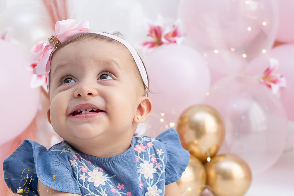 Ensaio smash the cake em estúdio. cenário com balões rosa e plumas. fotógrafo em Londrina especializado em ensaio de bebês e crianças. Ensaio de aniversário. Momento registrado pela fotografa Giscellayne - Gy Fotografia.