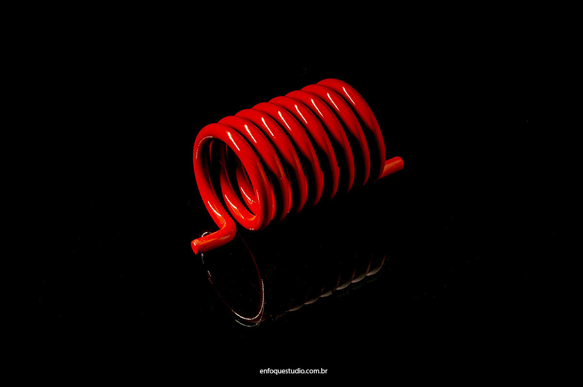 Fotografia Industrial de Molas para Torção em plano aberto e em fundo preto com reflexo para destacar formas dos produto