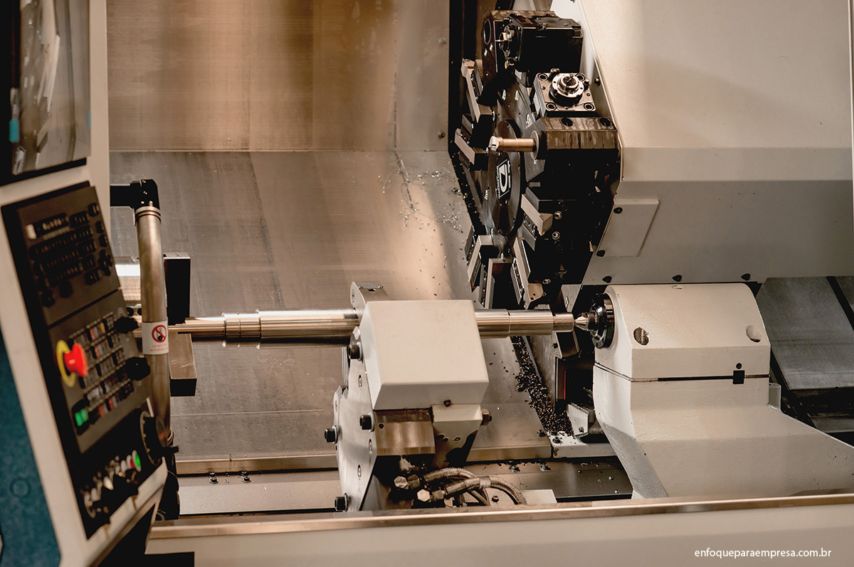 Fotografia de plano aberto com detalhes do torno e da peça sendo fabricada