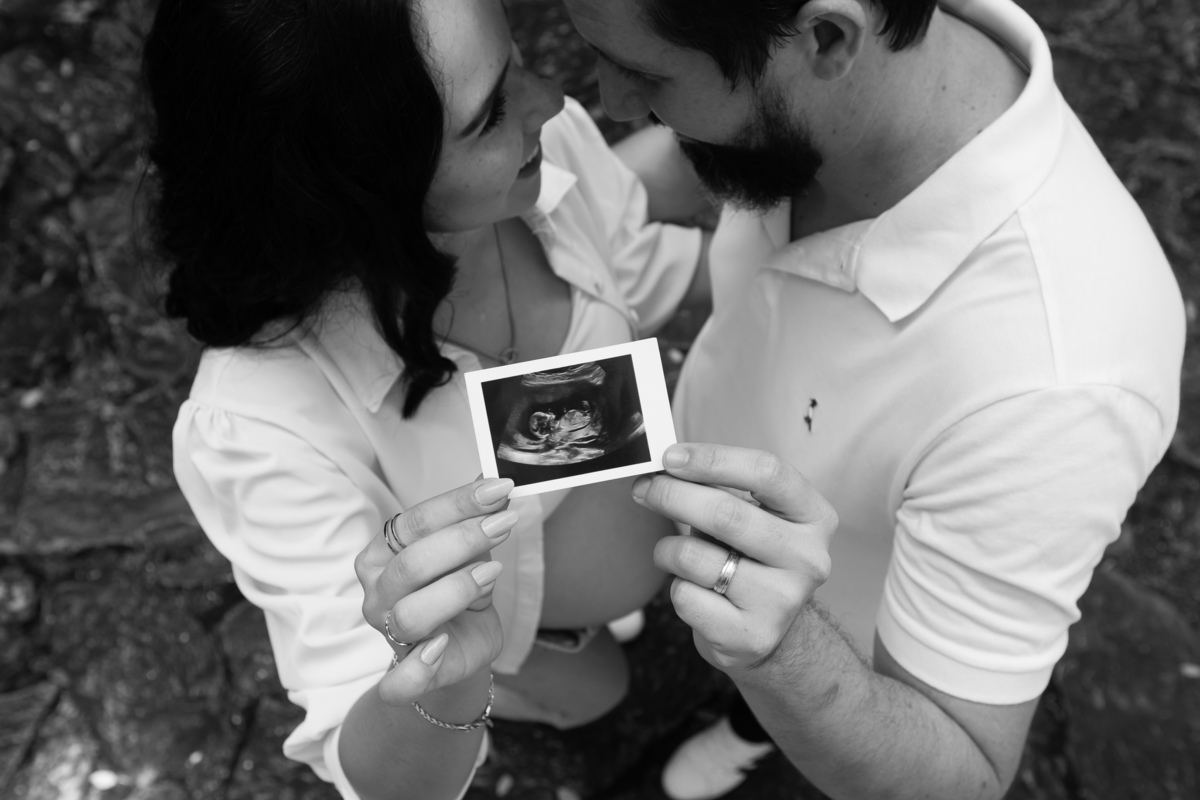 Casal segurando ultrassom do bebê durante ensaio gestante emocionante.