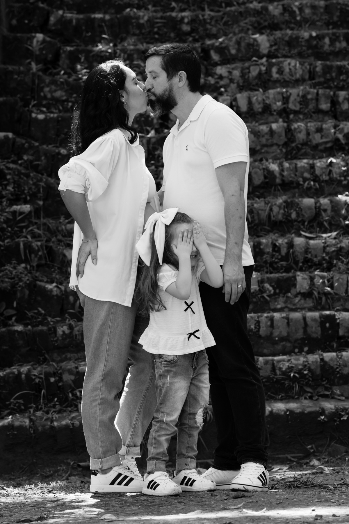 Filha fecha os olhos ao ver os pais se beijando no ensaio em família