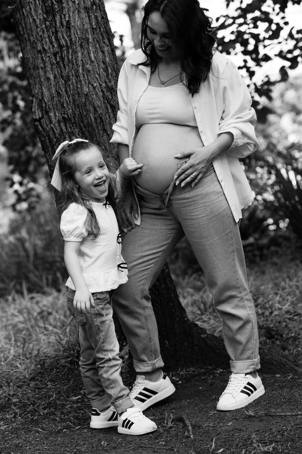 Filha demonstrando carinho pela barriga da mamãe durante ensaio gestante em família.