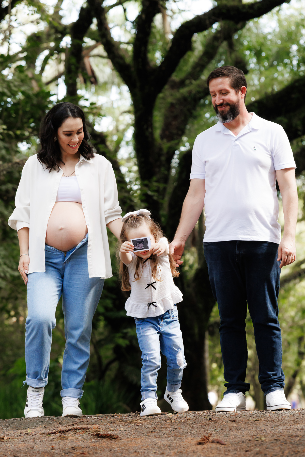 Família caminhando no parque durante ensaio gestante natural em Campinas.