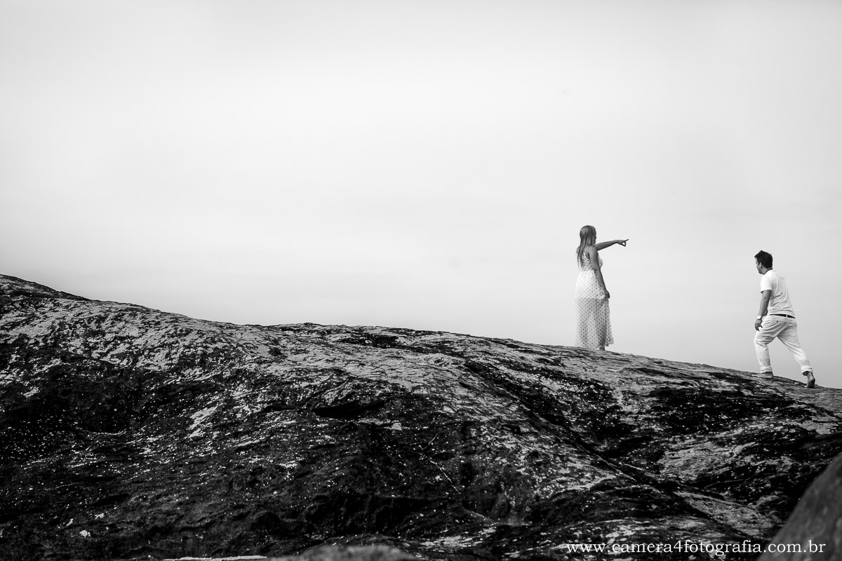 foto dos noivos nas pedras durante o ensaio na praia