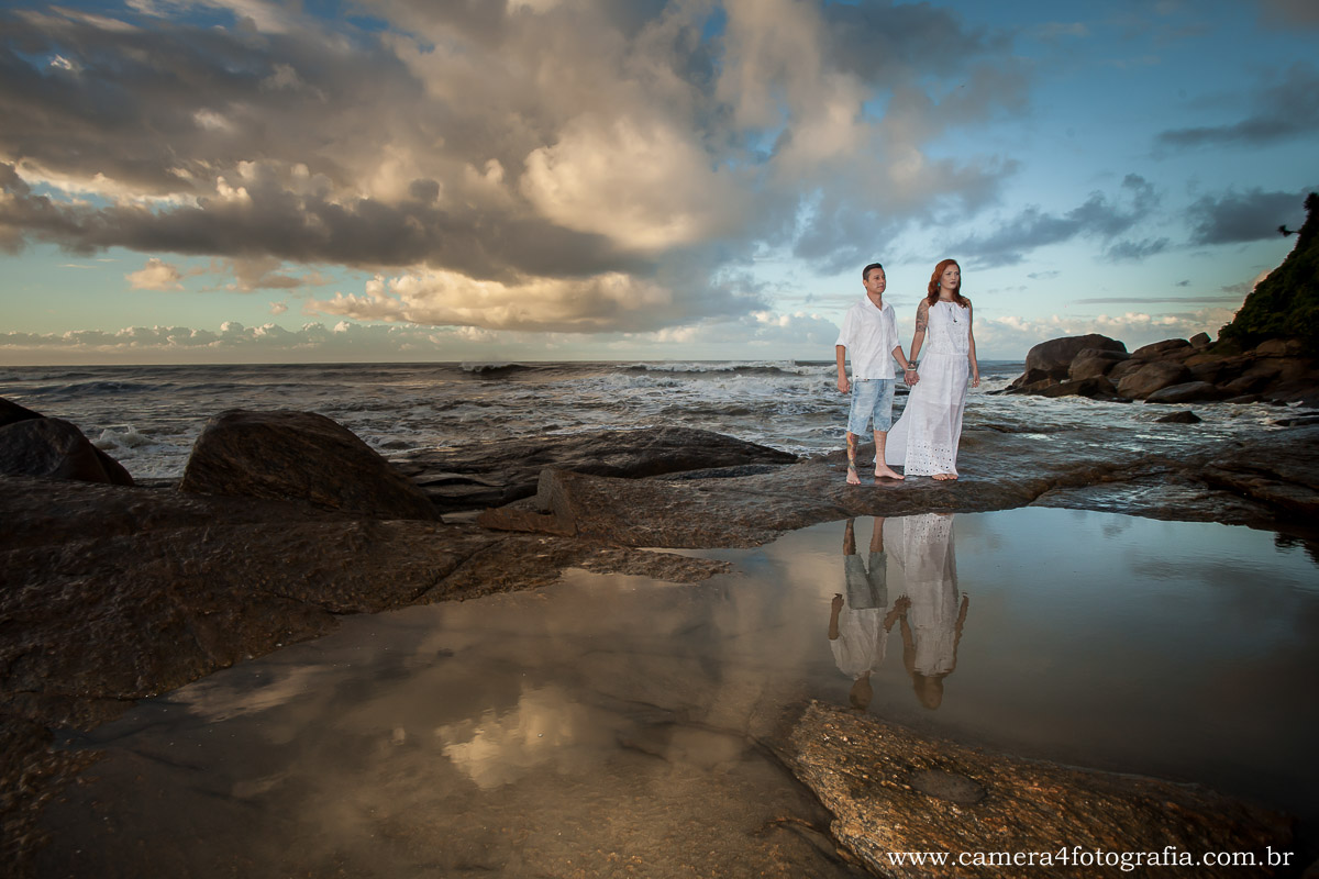 noivos na pedra na praia durante o ensaio pré casamento