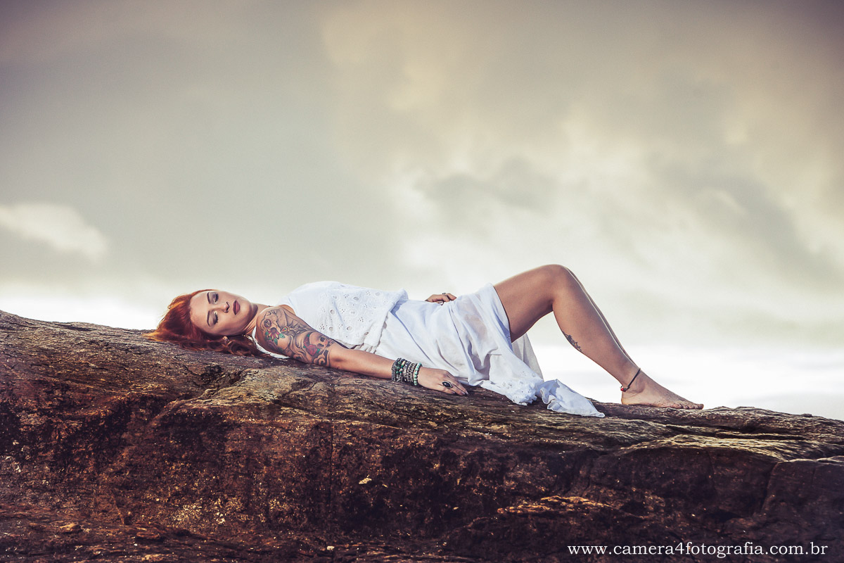 noiva deitada na pedra na praia no ensaio de pré casamento