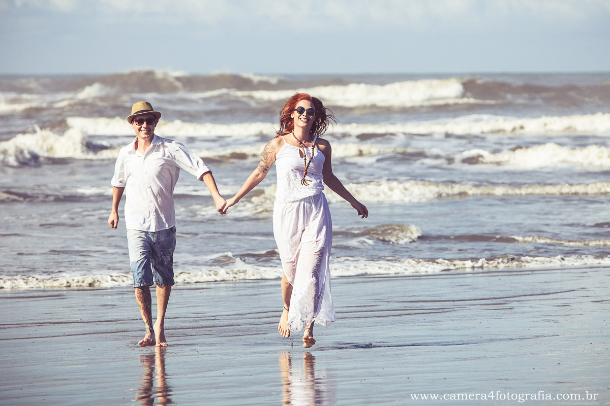 casal caminhando na praia durante o ensaio de noivos