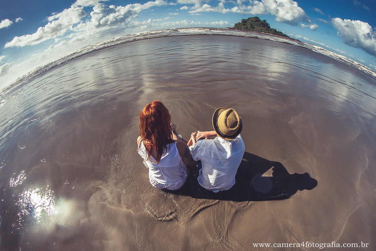 noivos sentados na areia da praia