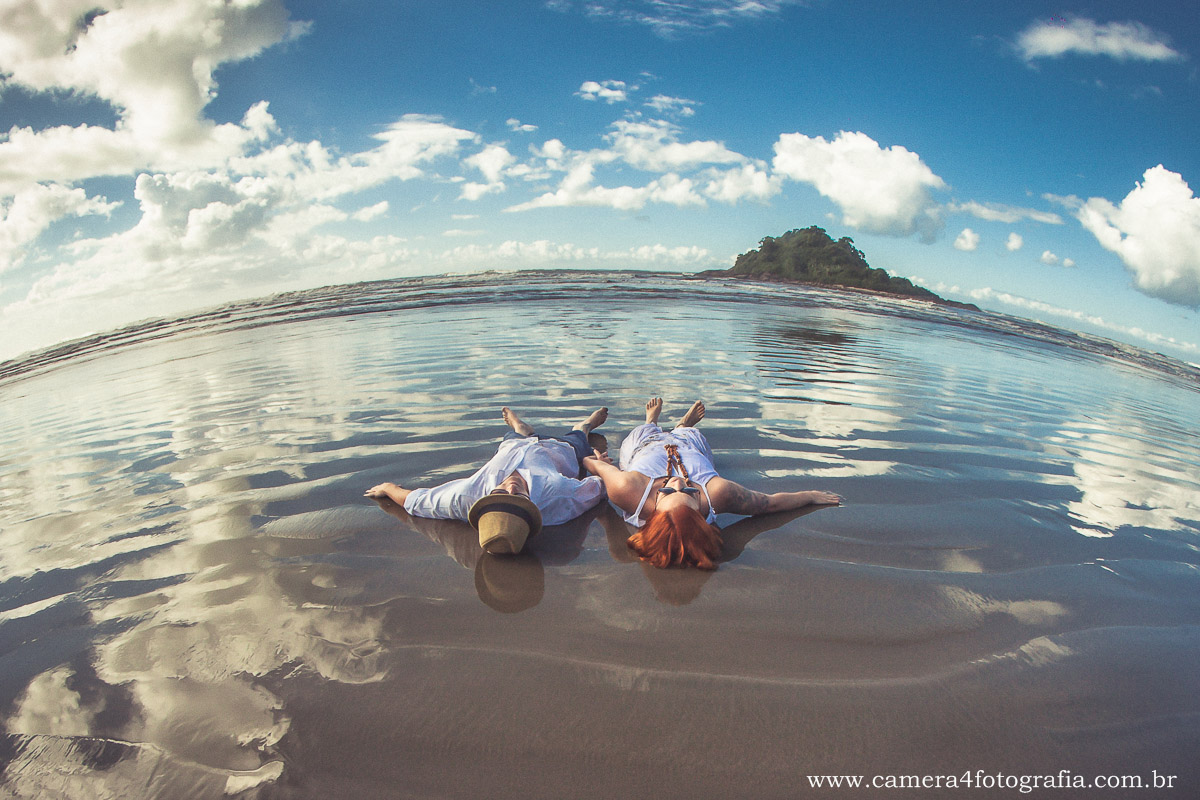 noivos deitados na areia durante o ensaio pré casamento