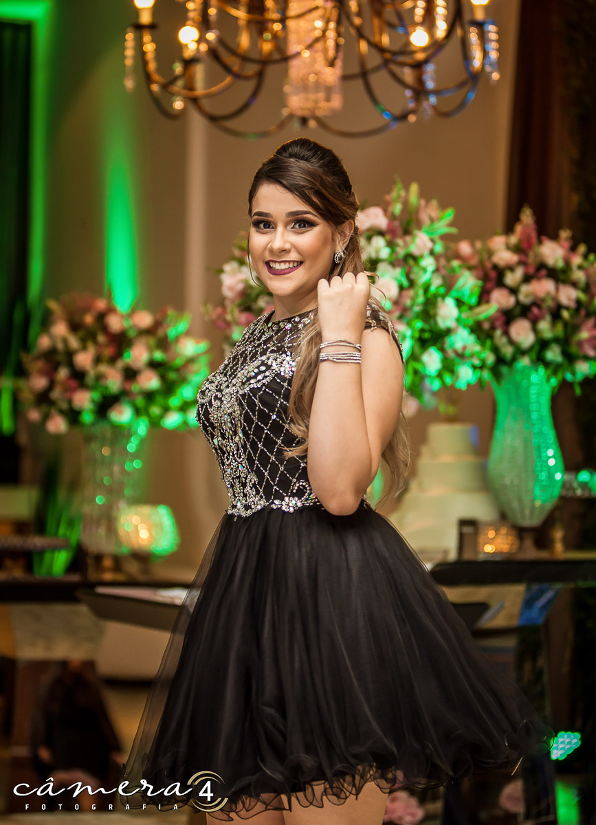 aniversariante na frente do bolo durante a festa de 15 anos