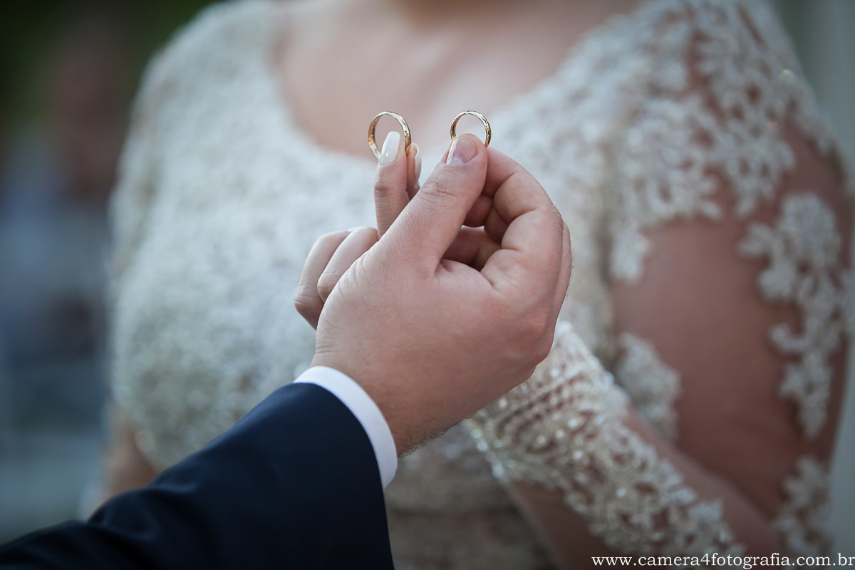 noivos com as alianças na mão durante a benção do padre no casamento