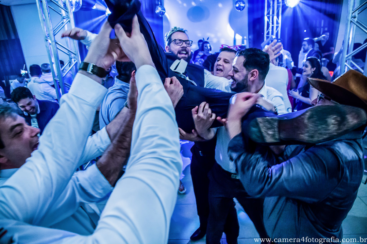 padrinhos jogando o noivo pra cima durante a festa do casamento