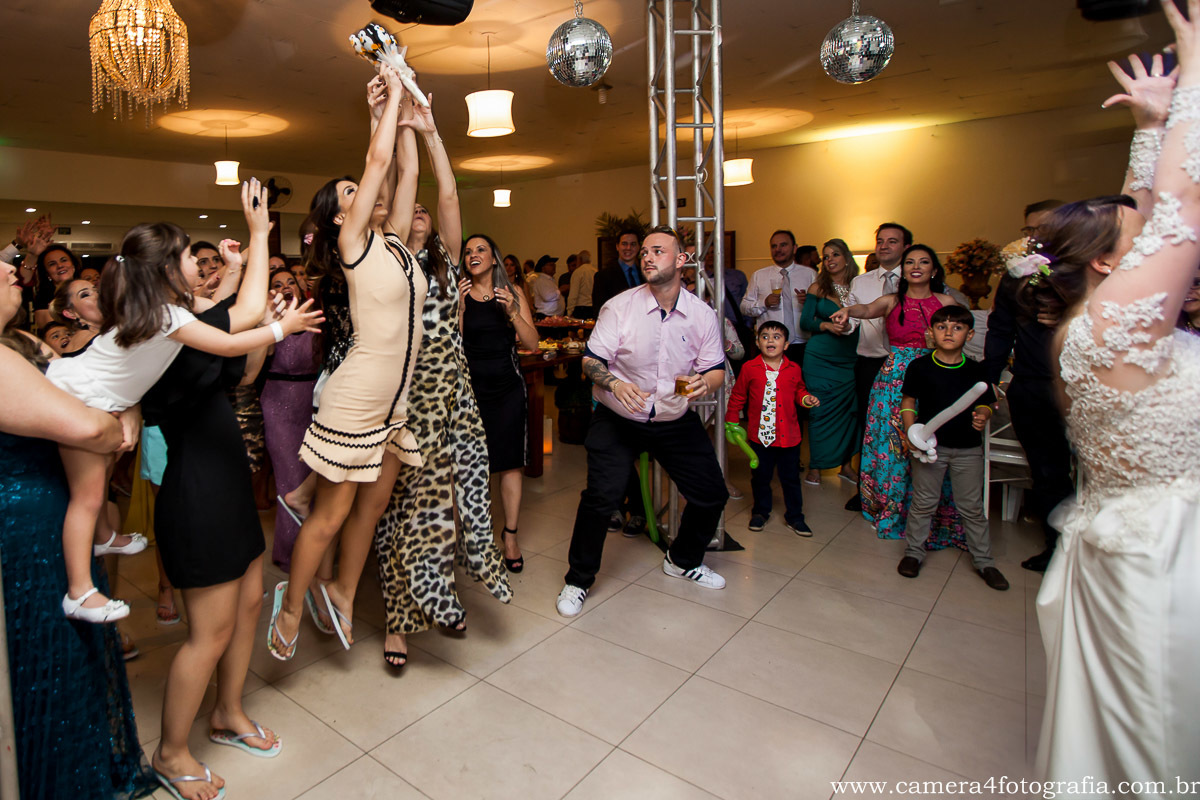 madrinha pulando para pegar o buquê da noiva