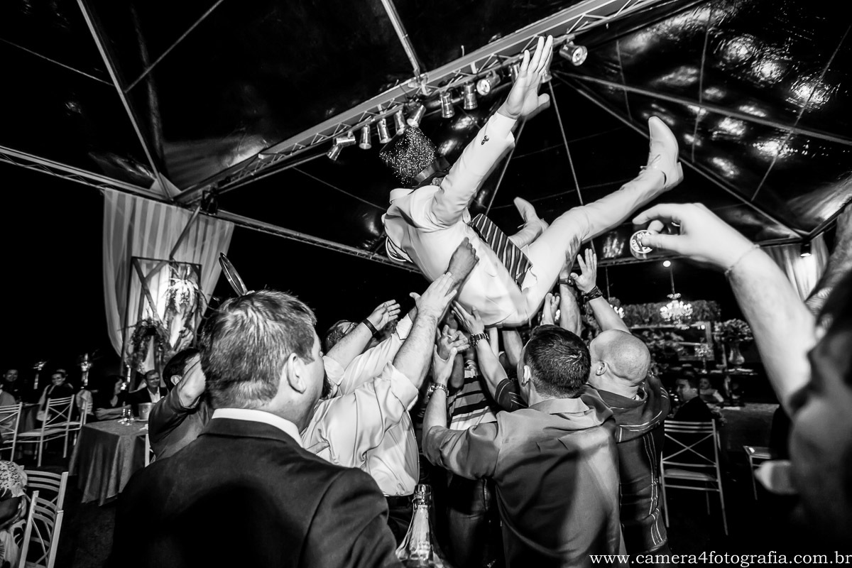 convidados jogando o noivo pra cima durante a festa do casamento
