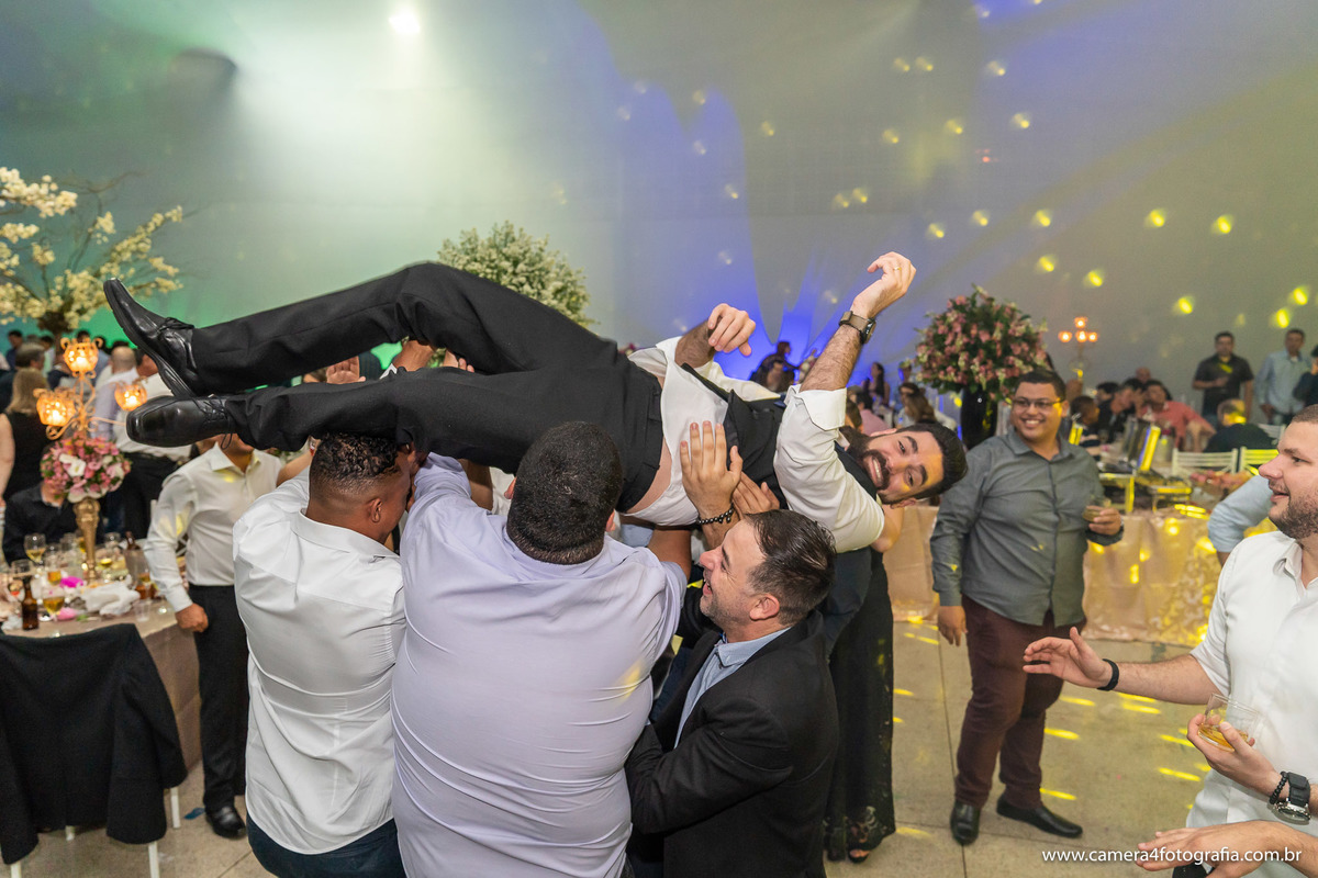 convidados jogando o noivo para o alto durante a festa do casamento