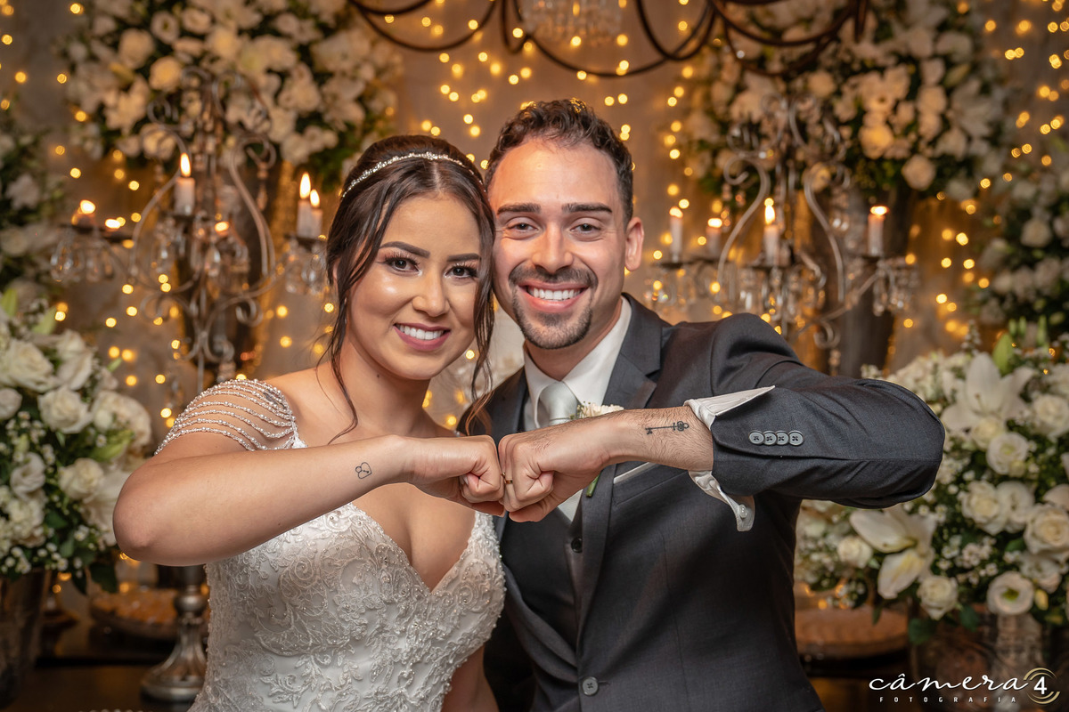 noivos posando para fotos na frente do bolo do casamento