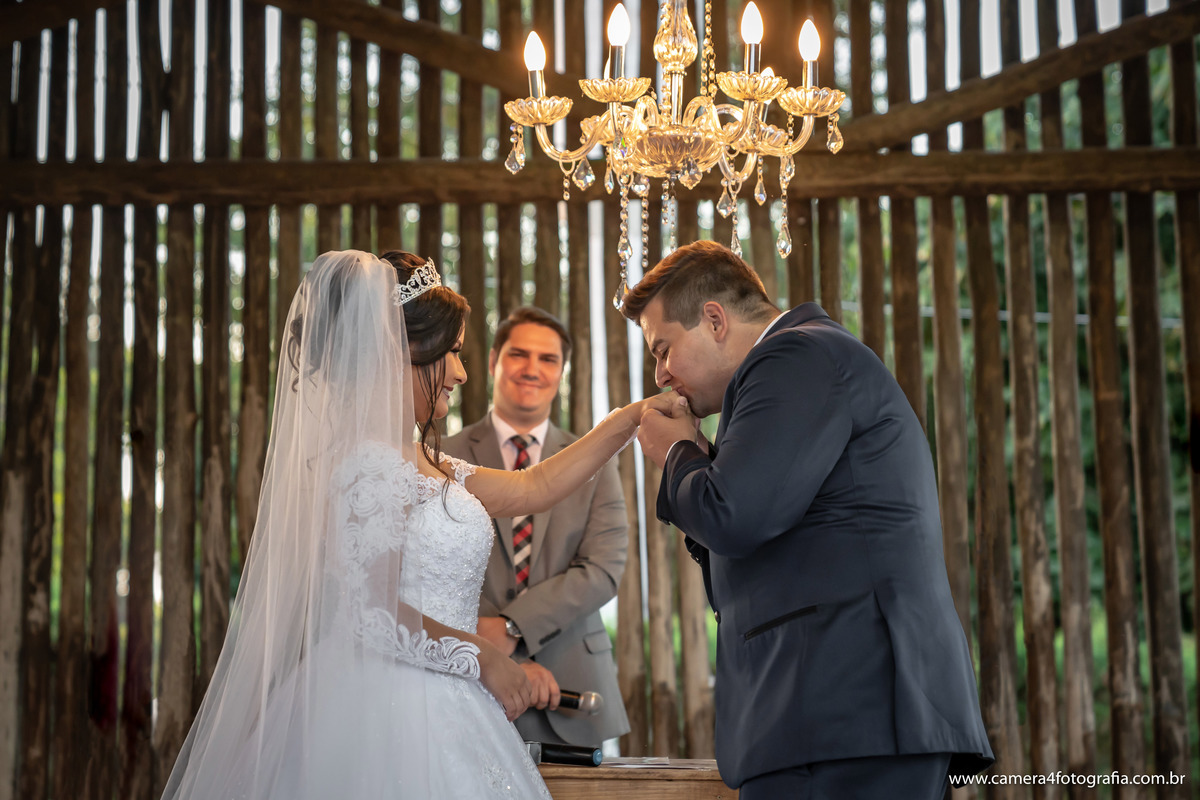 noivo beijando a mão da noiva durante a cerimônia de casamento ao ar livre em Bauru