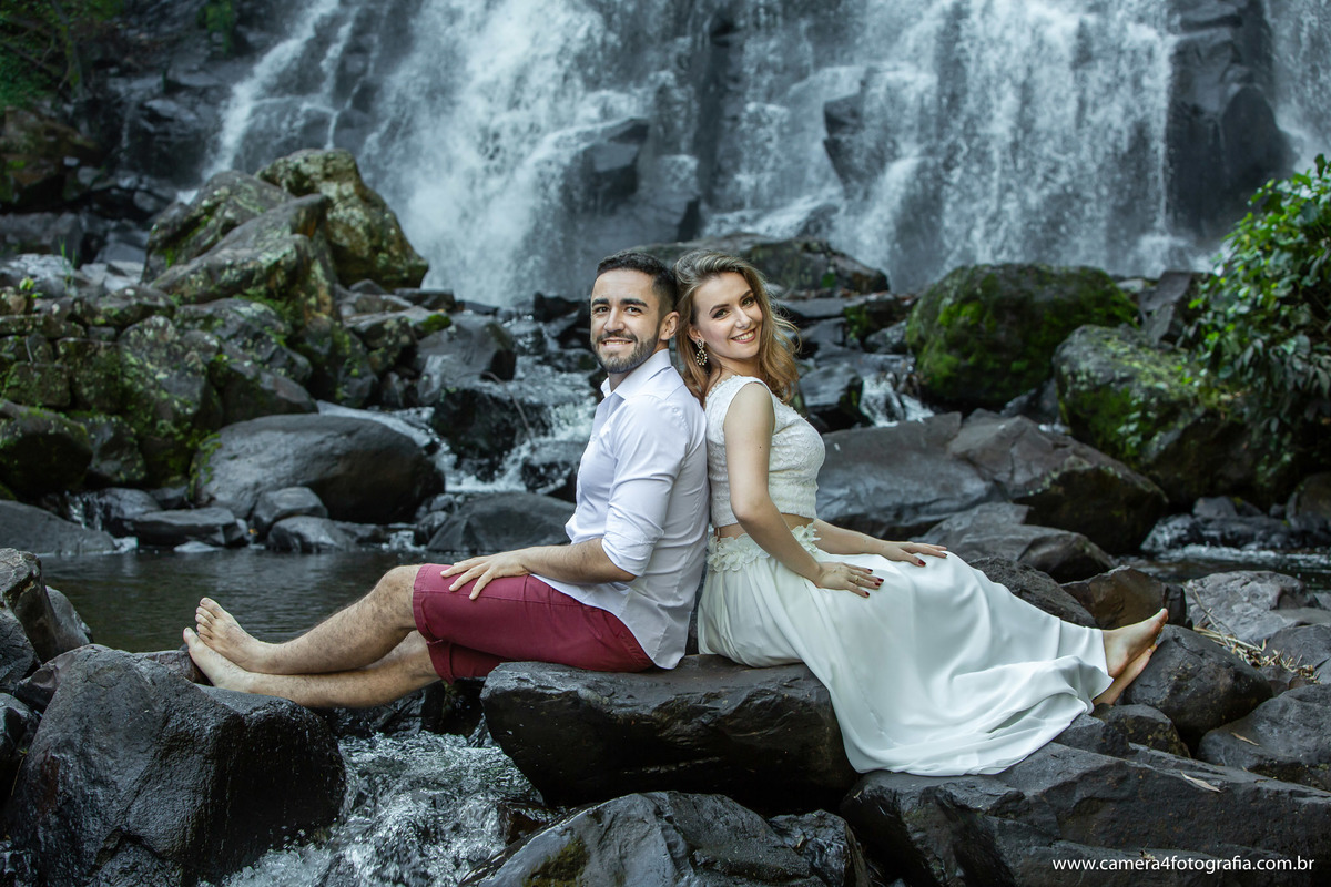 noivos sentados nas pedras da cachoeira em águas de santa bárbara