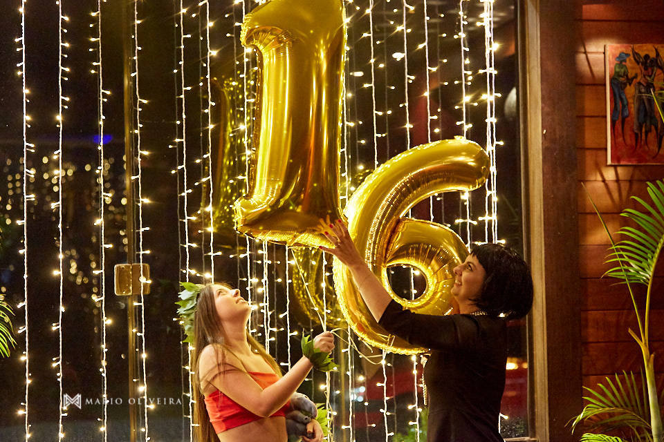 aniversariante brincando com balões com os números 16