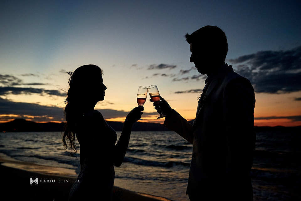 casal brindando em frente ao mar no por do sol