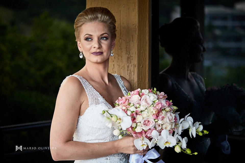 retrato da noiva em pé olhando para paisagem segurando o buque na varanda do hotel infinity blue resort balneario camboriu