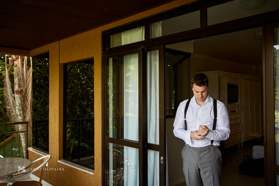 noivo de suspensórios abotoando punhos na varando infinity blue resort balneario camboriu no making of