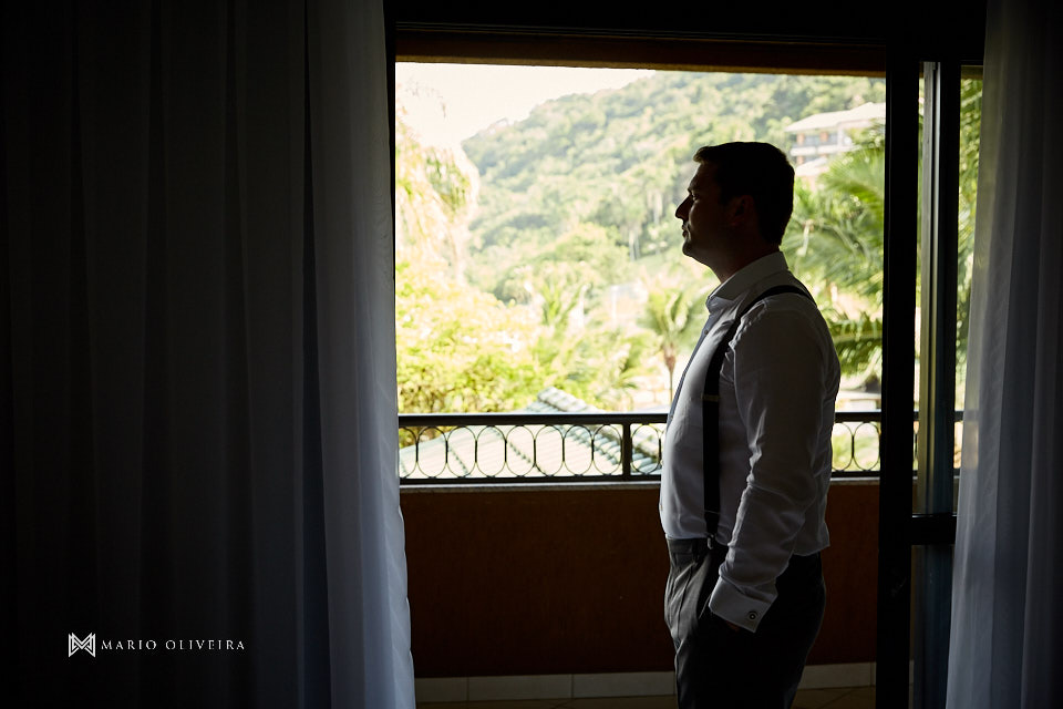 noivo em frente a janela infinity blue resort balneario camboriu com as mãos nos bolsos