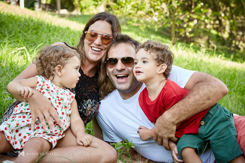 famlia brincando na grama, pais e filhos sorrindo