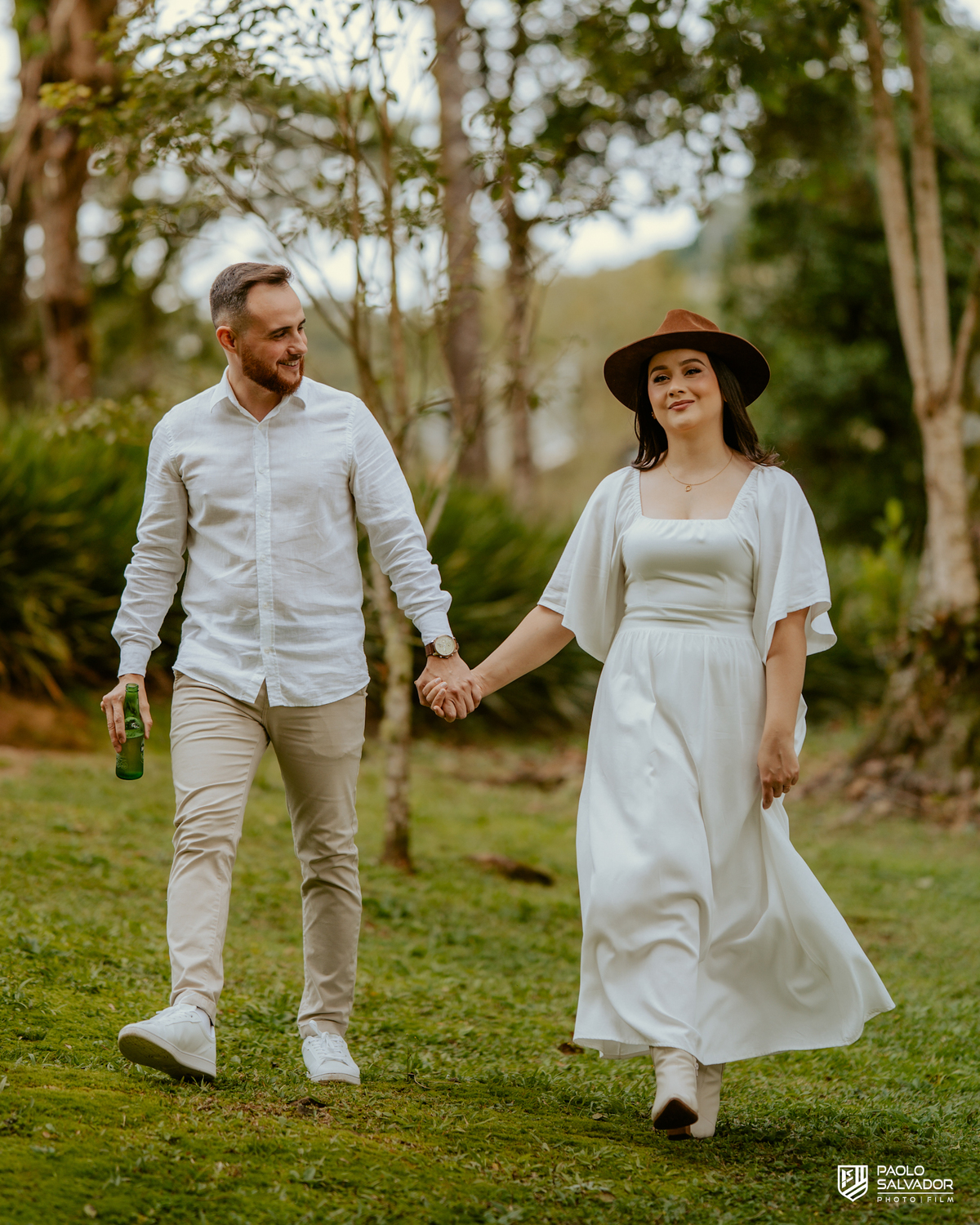 Casal caminhando à beira do lago no Vale dos Ventos Rio dos Cedros SC, ensaio pré wedding romântico com montanhas ao fundo, fotógrafo de casamento Santa Catarina, fotos naturais e espontâneas pré casamento