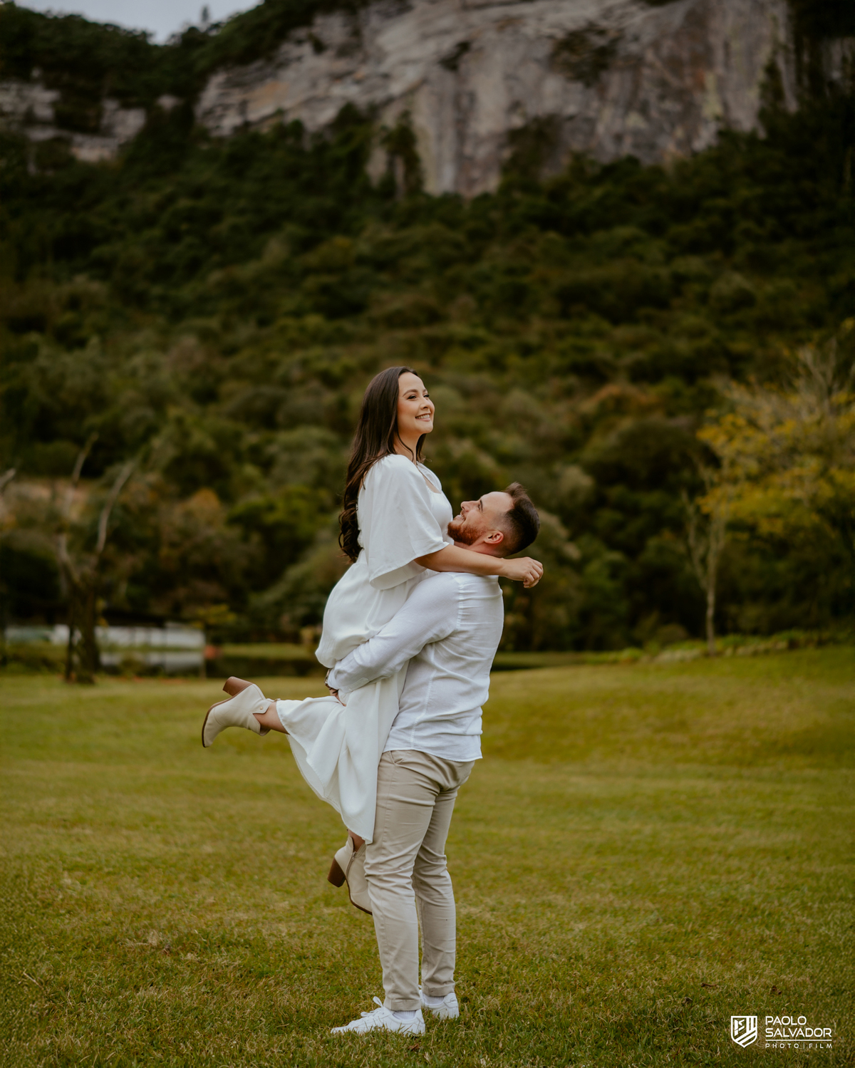 Casal caminhando à beira do lago no Vale dos Ventos Rio dos Cedros SC, ensaio pré wedding romântico com montanhas ao fundo, fotógrafo de casamento Santa Catarina, fotos naturais e espontâneas pré casamento