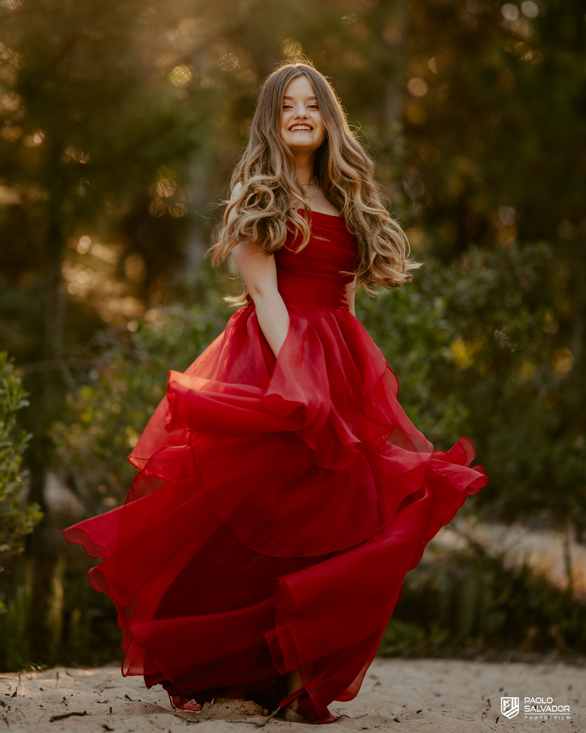 Ensaio de 15 anos com vestido vermelho rodando em Florianópolis SC, debutante sorrindo em cenário natural, fotógrafo de debutante Santa Catarina, ensaio feminino leve e espontâneo na natureza