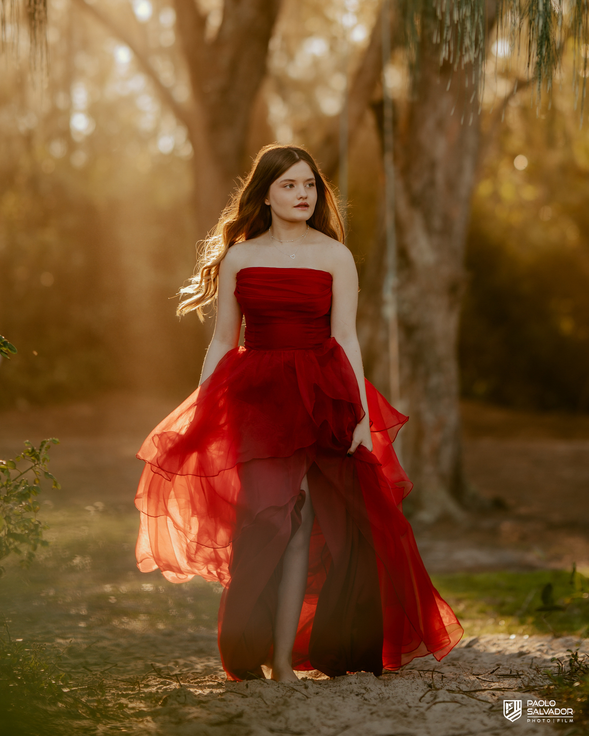 Retrato de debutante em ensaio de 15 anos em Florianópolis SC, menina com vestido vermelho e fundo desfocado na natureza, fotógrafo de debutante Santa Catarina, ensaio feminino ao ar livre Praia do Moçambique