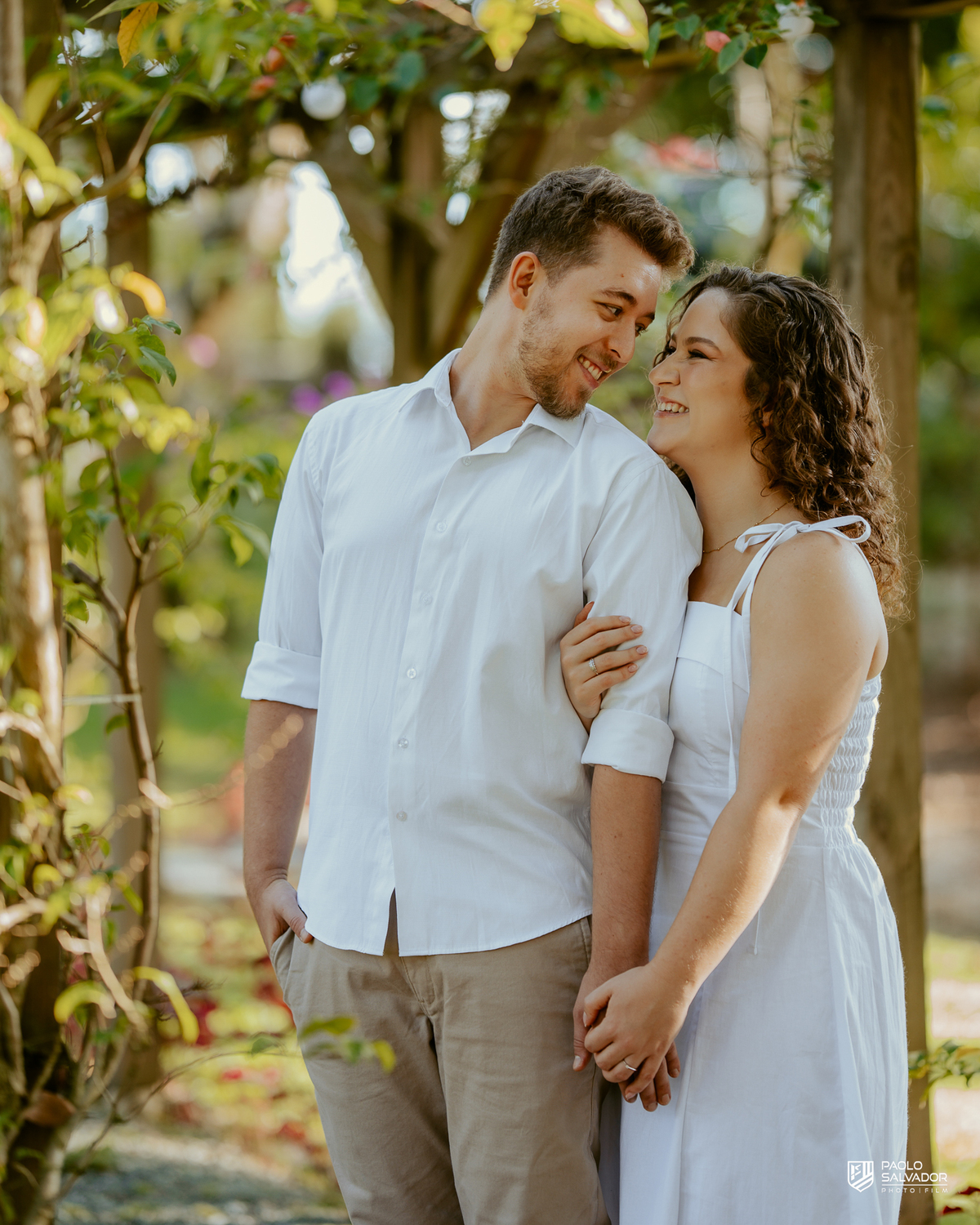 Casal abraçado em cerca de madeira no Morro São Bernardo em Rio dos Cedros durante ensaio pré-wedding, com luz suave e clima romântico, ideal para ensaios próximos às barragens.