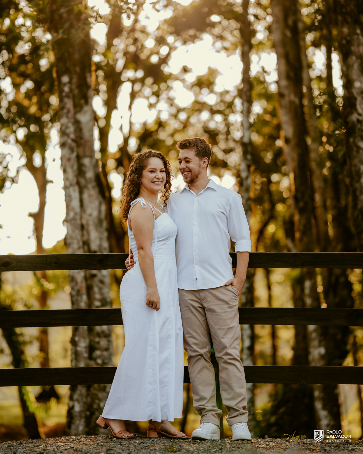 Casal posando em estrada cercada por árvores durante ensaio pré-wedding em Rio dos Cedros, com estética natural e romântica, referência para ensaios na Barragem Rio Bonito e Altos Cedros.