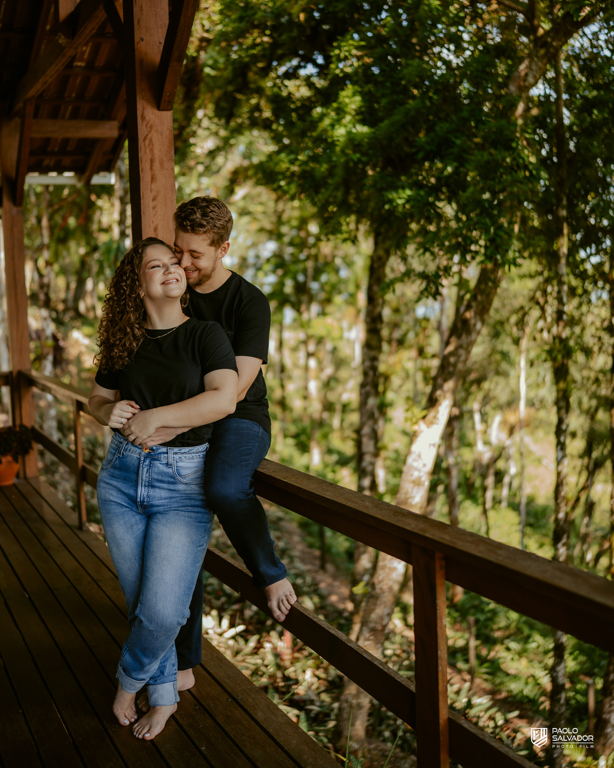 Casal em ensaio pré-wedding em Rio dos Cedros nas Cabanas Morro São Bernardo, abraçados em deck de madeira com natureza ao redor, luz suave e clima romântico, referência para ensaios na Barragem Rio Bonito, Palmeiras e Altos Cedros.
