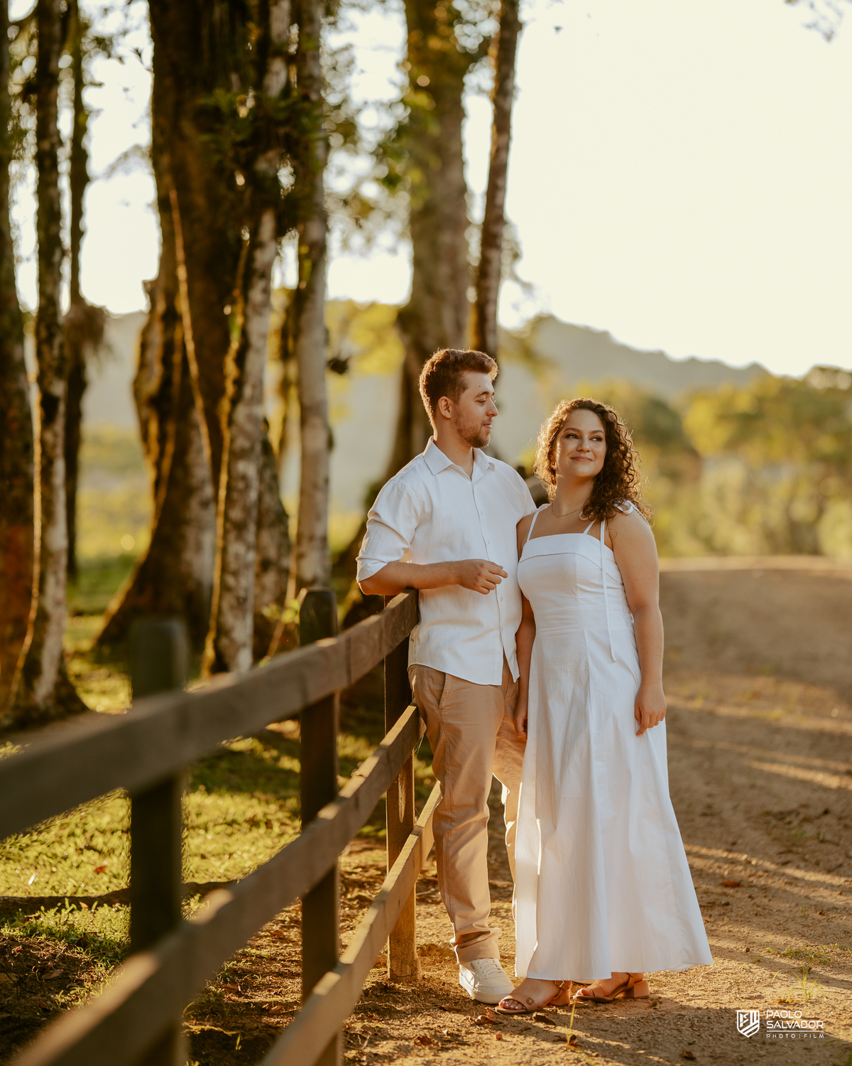 Casal sorrindo e abraçado em ensaio pré-wedding em Rio dos Cedros com fundo desfocado e luz dourada, destacando emoção e conexão, ideal para ensaios nas barragens e arredores.