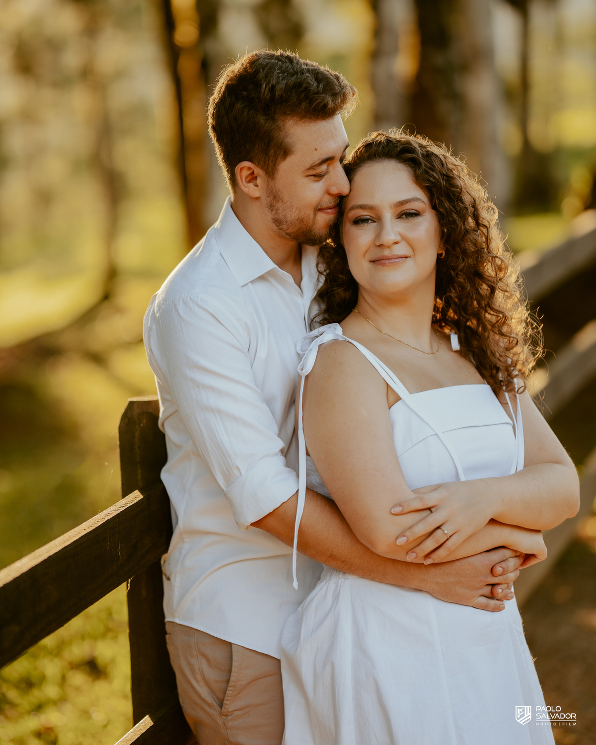 Casal sorrindo e abraçado em ensaio pré-wedding em Rio dos Cedros com fundo desfocado e luz dourada, destacando emoção e conexão, ideal para ensaios nas barragens e arredores.