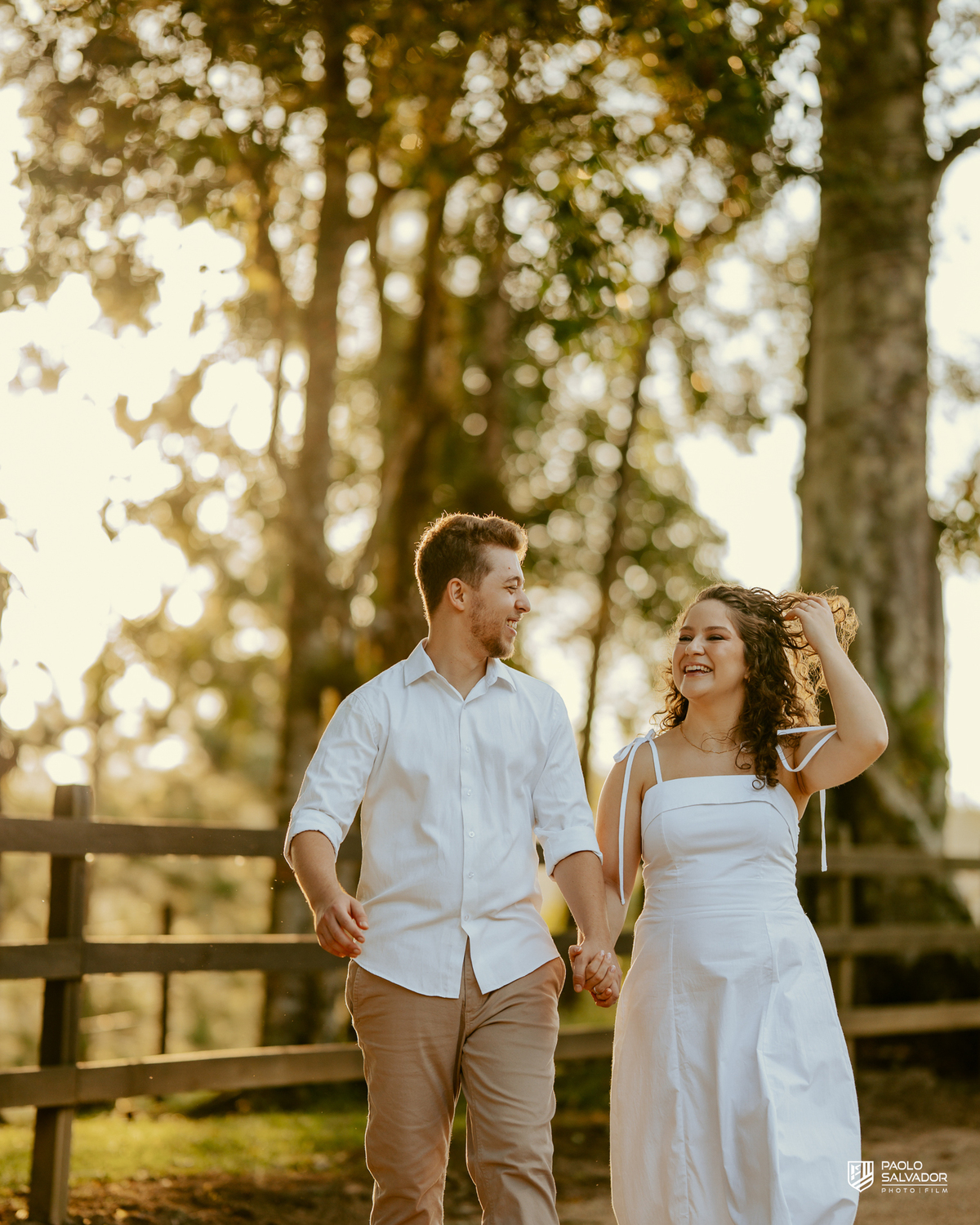 Casal sorrindo e abraçado em ensaio pré-wedding em Rio dos Cedros com fundo desfocado e luz dourada, destacando emoção e conexão, ideal para ensaios nas barragens e arredores.