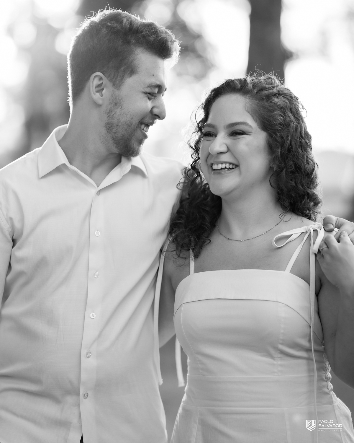 Casal sorrindo e abraçado em ensaio pré-wedding em Rio dos Cedros com fundo desfocado e luz dourada, destacando emoção e conexão, ideal para ensaios nas barragens e arredores.