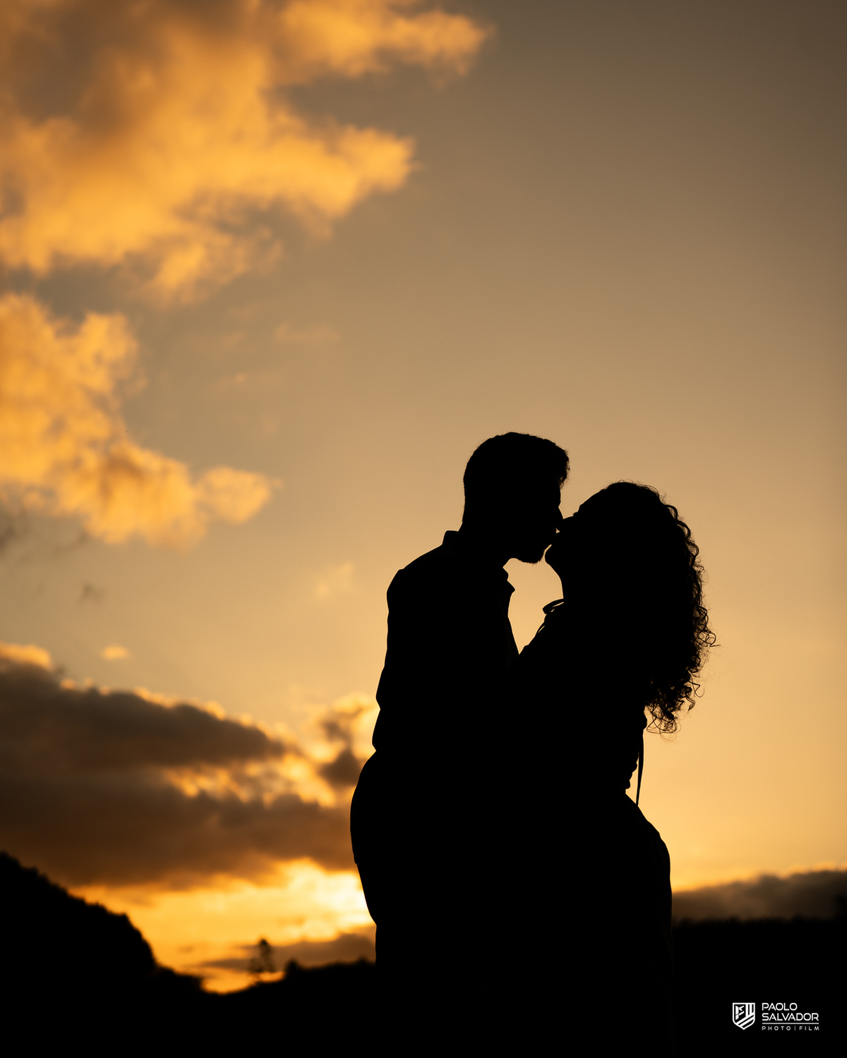 Silhueta de casal ao pôr do sol em ensaio pré-wedding em Rio dos Cedros, com céu dramático e estética cinematográfica, ideal para quem busca ensaios nas barragens e Altos Cedros.