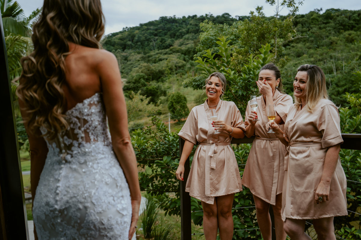 Noiva brindando com madrinhas no chalé do Refúgio dos Lagos em Massaranduba, momento descontraído e elegante antes da cerimônia, inspiração para casamentos em Joinville, Jaraguá e região.
